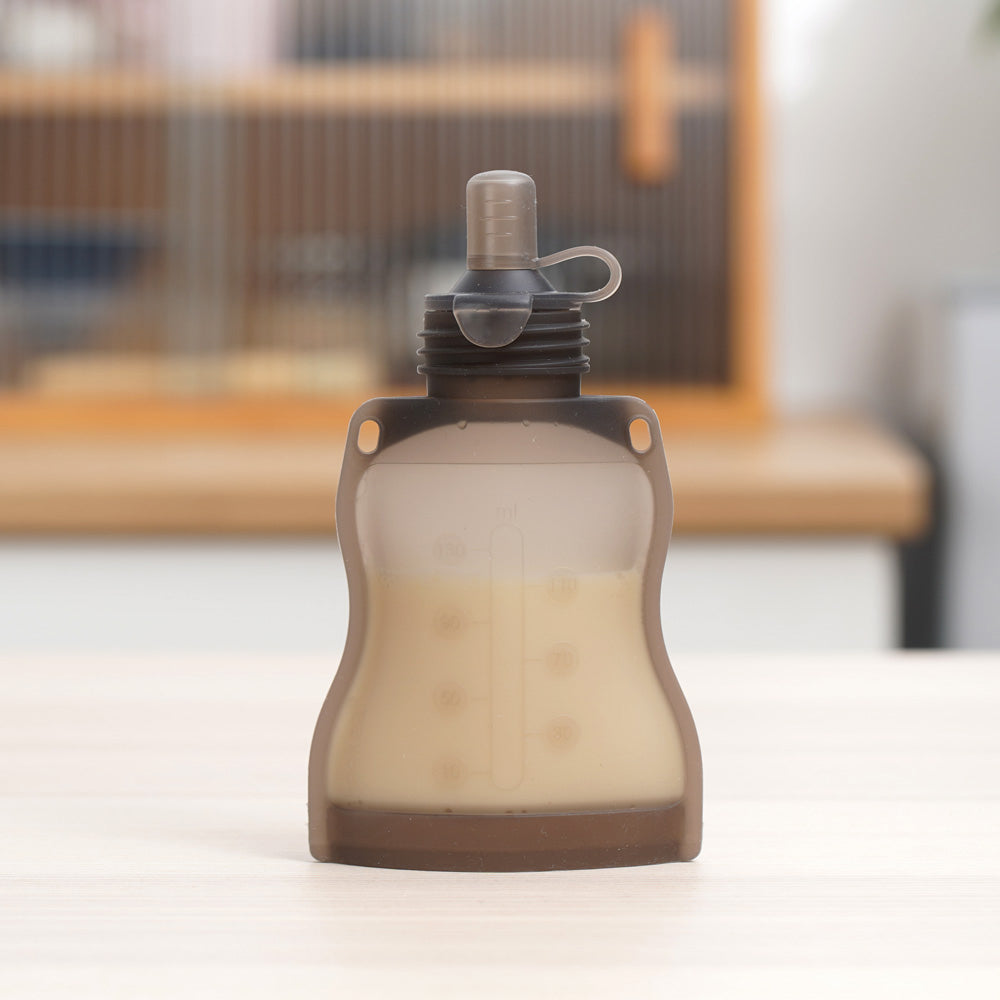 Reusable baby food pouch filled with puree standing upright showing clear capacity markings