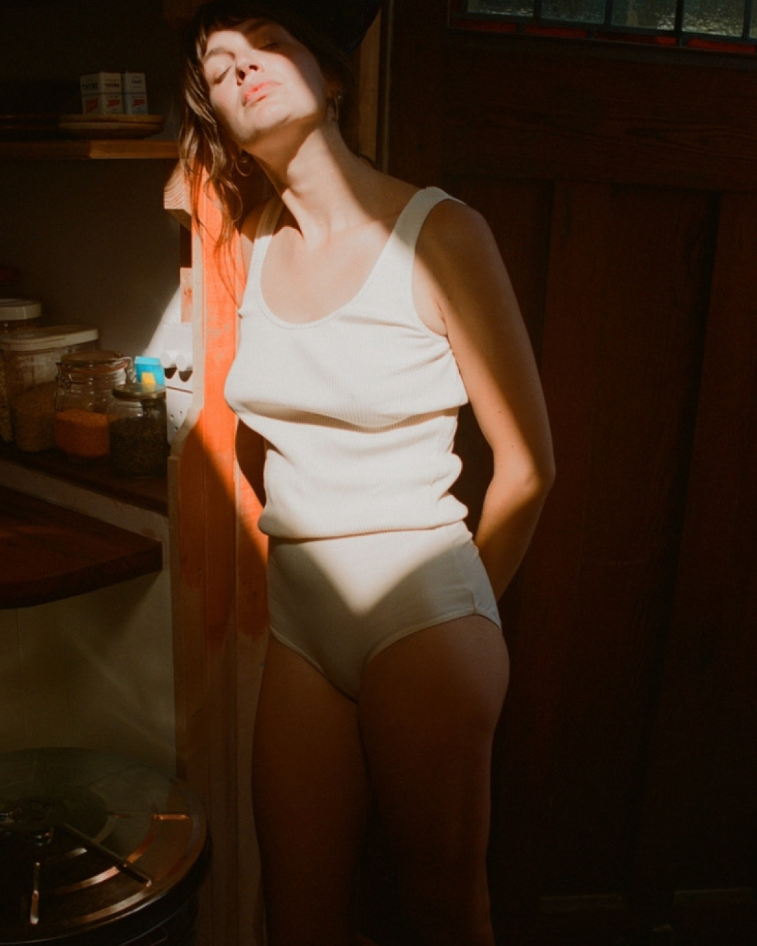 Woman relaxing in natural white organic cotton underwear set warm morning light lifestyle