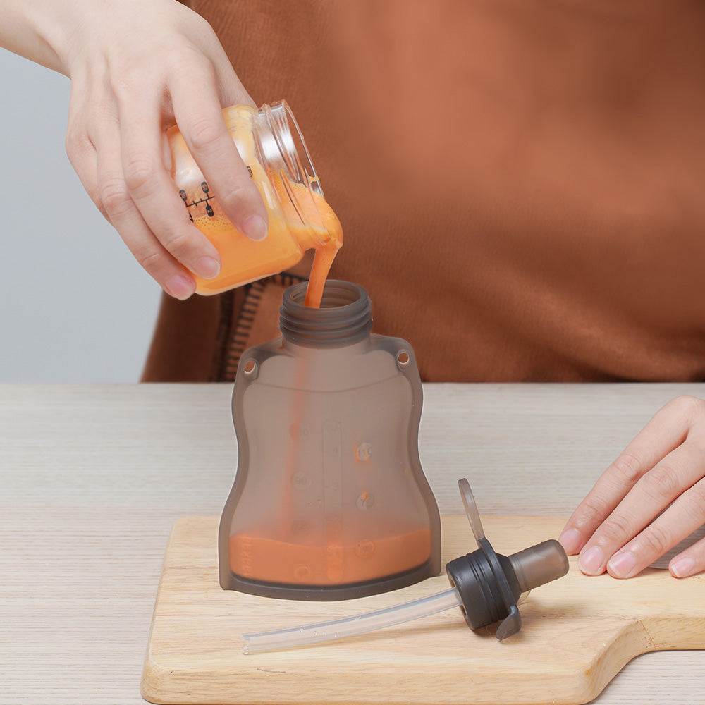 Pouring baby puree into reusable silicone food pouch through wide neck opening for easy filling