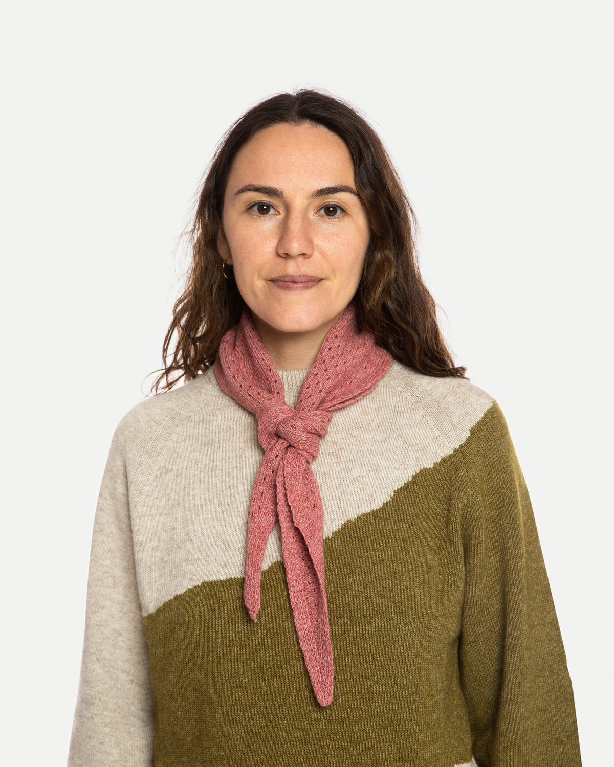 Woman wearing a pink scarf and a two-tone sweater on a white background