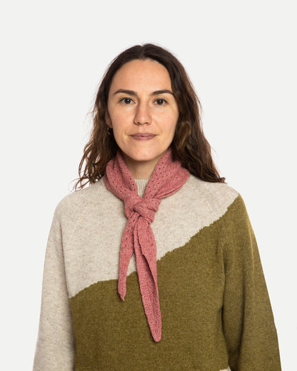 Woman wearing a pink scarf and a two-tone sweater on a white background