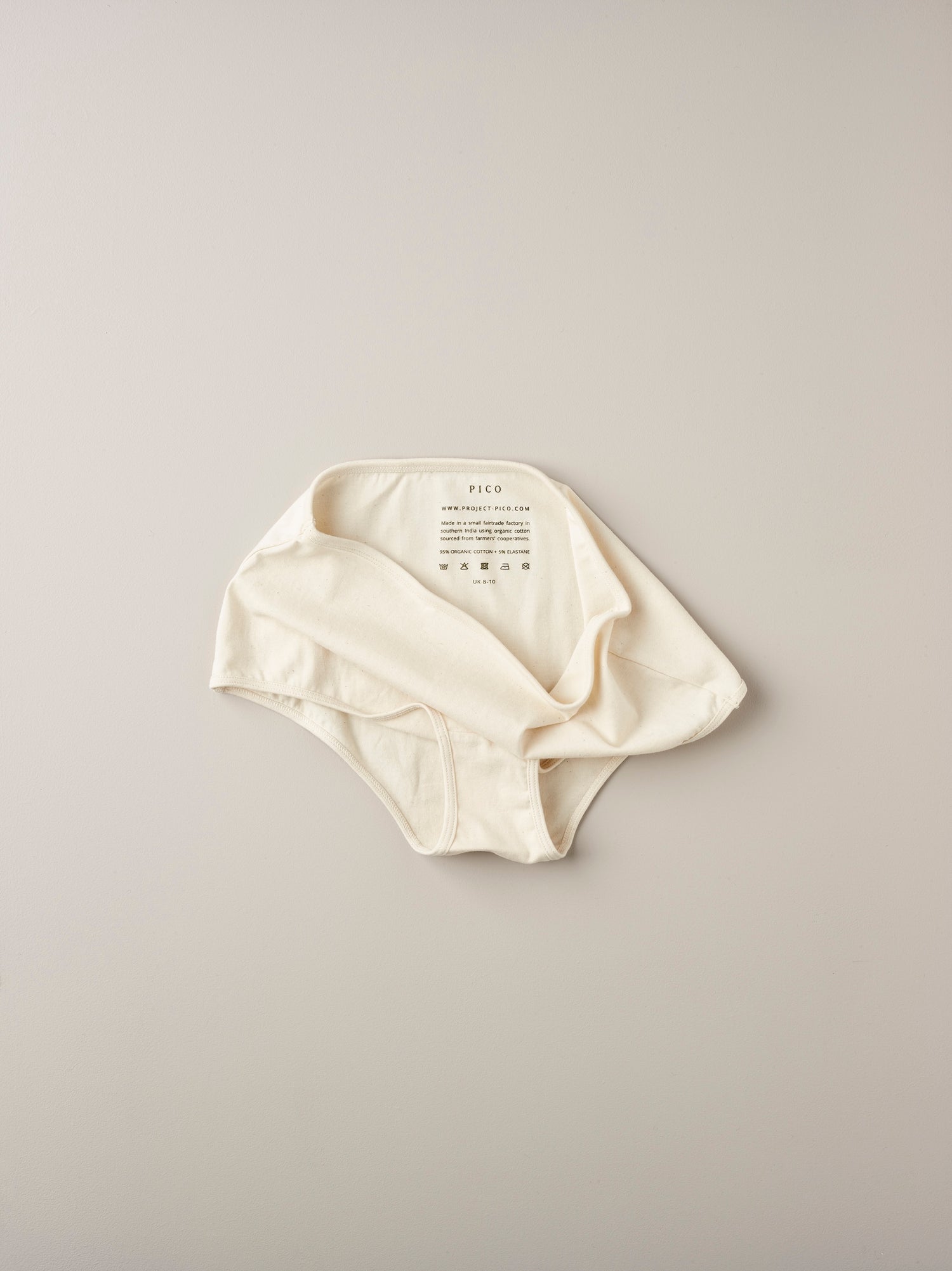 Pico organic cotton high-waisted briefs in natural white folded showing care label and soft texture