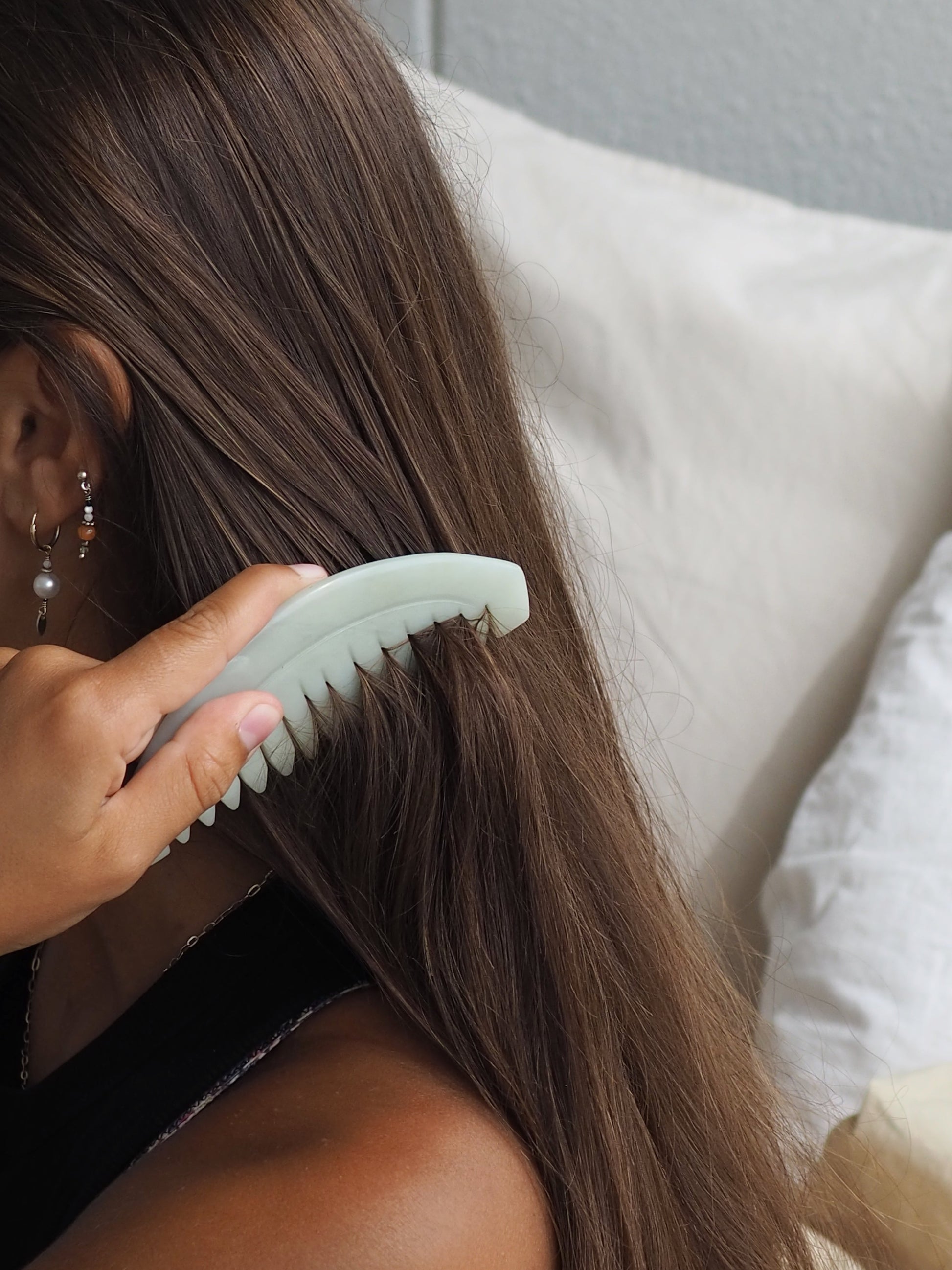 Mellow Mind jade gua sha comb gliding through long hair for gentle scalp massage and detangling